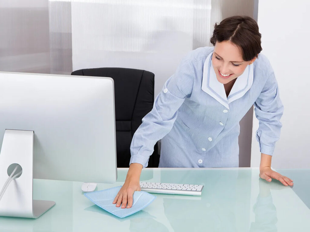 Smiling office cleaner sanitizing desk for cleaning company in Los Gatos, CA